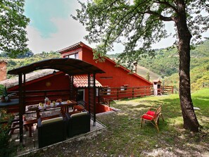 A red building with a covered patio area, a wooden fence, and a chair.
