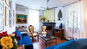 A living room with a blue sofa, a chair, a coffee table, and a fireplace. - Belvilla by OYO Villa Nicola (Ricadi)