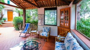 A covered patio with a wooden ceiling, wicker furniture, and a glass table. - Belvilla by OYO Villa Nicola (Ricadi)