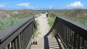 Un paseo marítimo de madera que lleva a una playa con vista despejada al océano.