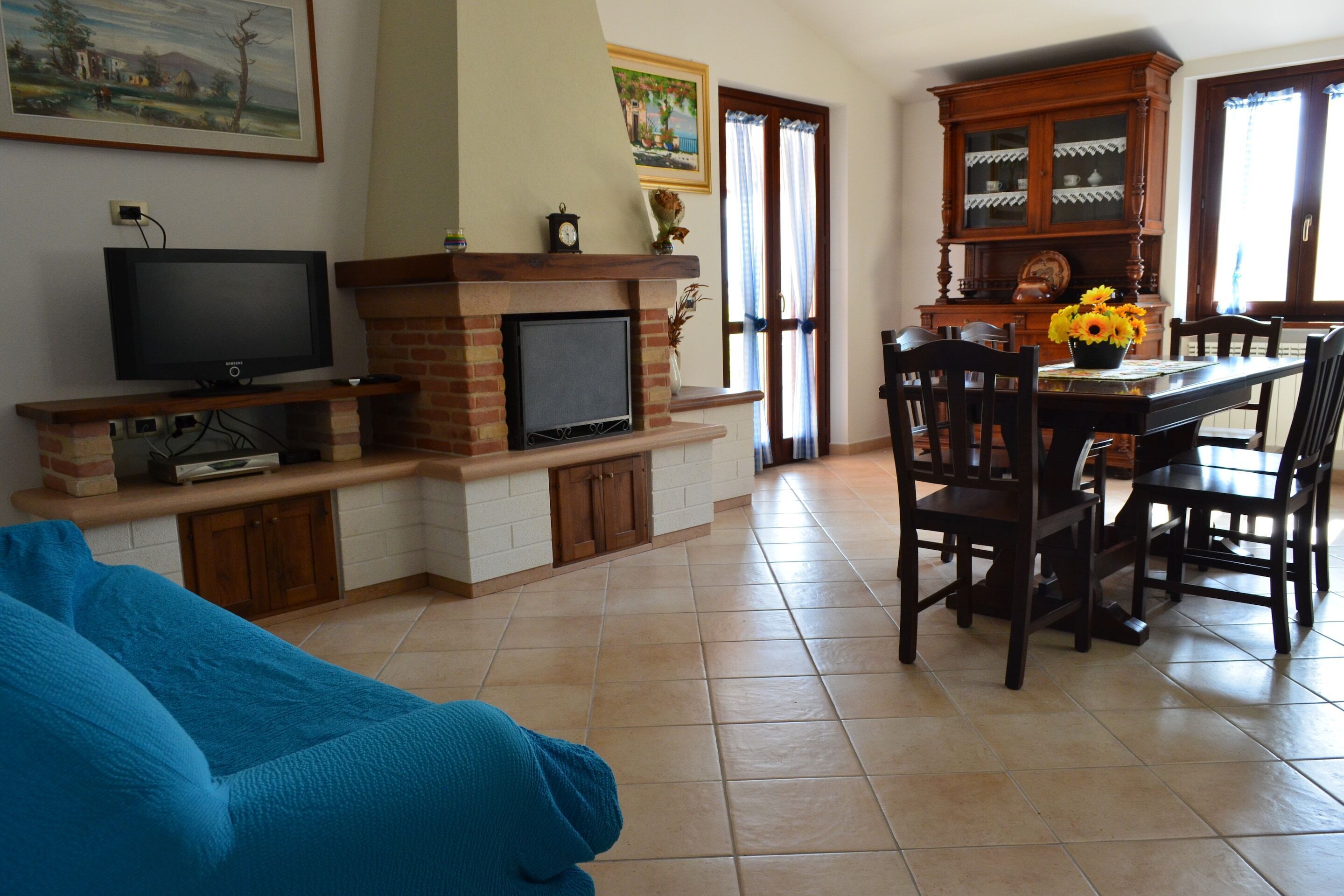 A living room with a fireplace, television, dining table, and chairs.