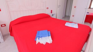 A room with a red bedspread, a white headboard, and a door with a red 'C' marking. - Villa in Marche With Pool & Panoramic Views (Acqualagna)