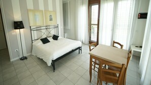 A hotel room with a bed, a desk, chairs, a lamp, and curtains. - Apartment in Tuscany Near Chianti Vineyards (Barberino Tavarnelle)