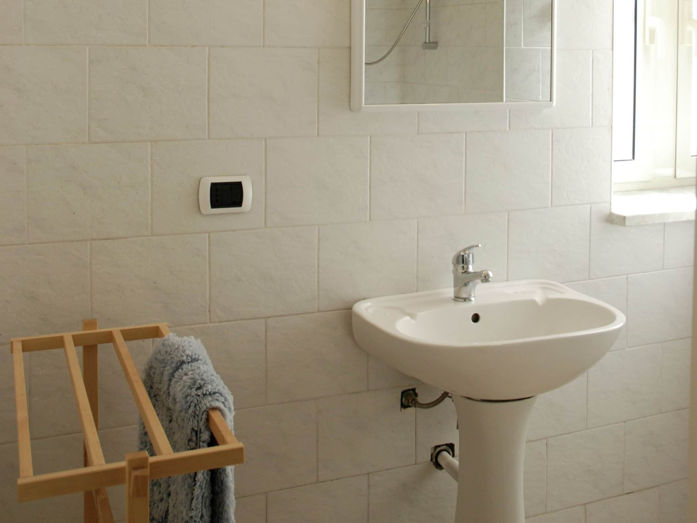 Une salle de bain avec un lavabo blanc, un miroir et un porte-serviettes.