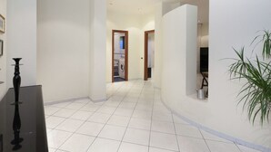 A spacious hallway with white tiled flooring, a black table, and a potted plant. - Cozy Holiday Home in Trecase With Balcony - Casa per Ferie (Trecase)