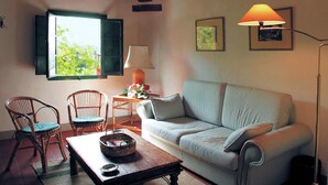 A cozy living room with a sofa, two chairs, a table with a basket, a lamp, and a window with shutters. - Spacious Tuscan Farmhouse (Peccioli)