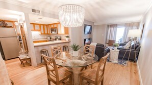 A modern kitchen with wooden cabinets, a central island, and a dining area with a glass table and wooden chairs. - Oceanfront-402-- 3 Bedroom / 2 Bath Condo pet friendly in North Myrtle Beach (North Myrtle Beach)