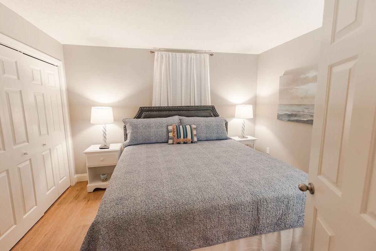 Un dormitorio con cama, lámparas de noche, mesita de noche y una puerta.