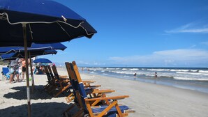 A beach with rows of wooden beach chairs and umbrellas, a sandy shoreline, and the ocean in the background. - Oceanfront-402-- 3 Bedroom / 2 Bath Condo pet friendly in North Myrtle Beach (North Myrtle Beach)