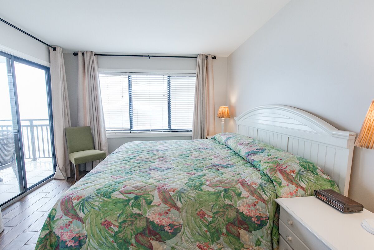 A bedroom with a bed, a chair, a nightstand, and a window with curtains.