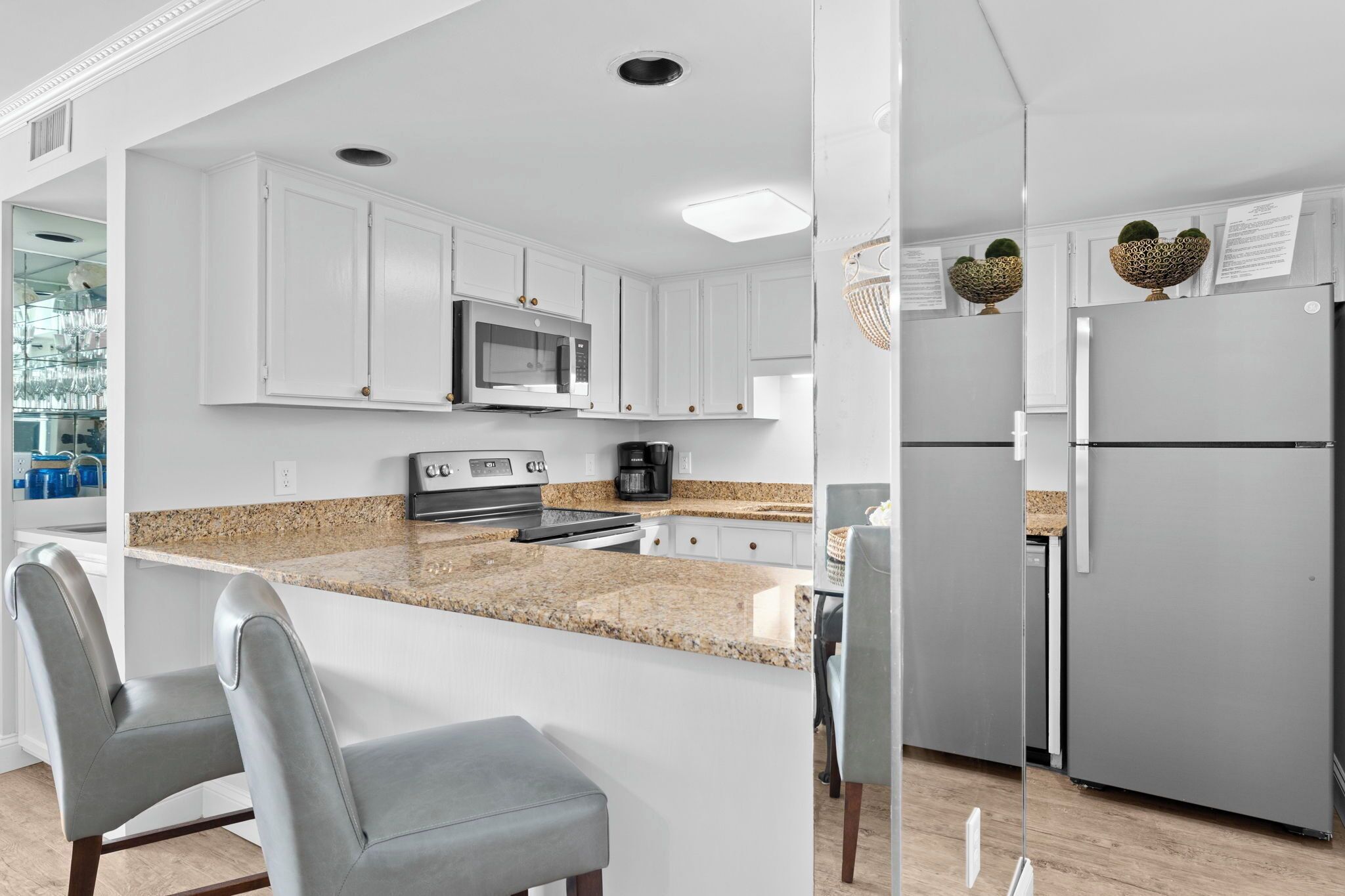 A modern kitchen with white cabinets, a granite countertop, stainless steel appliances, and a built-in island with seating.