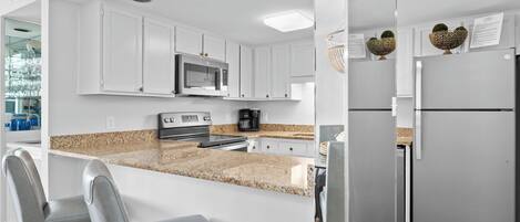 A modern kitchen with white cabinets, a granite countertop, stainless steel appliances, and a built-in island with seating.