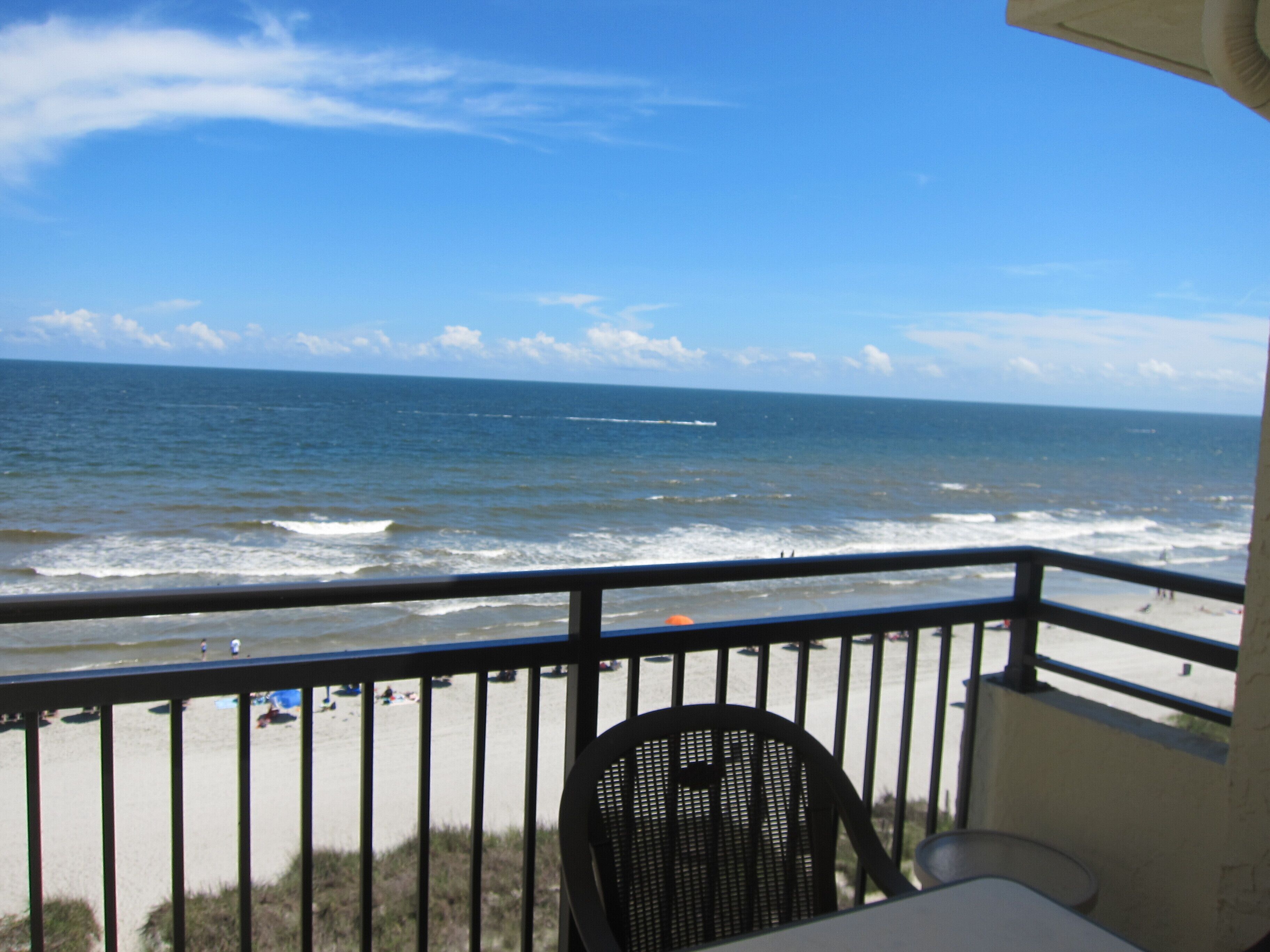 A balcony with a view of the ocean and beach.