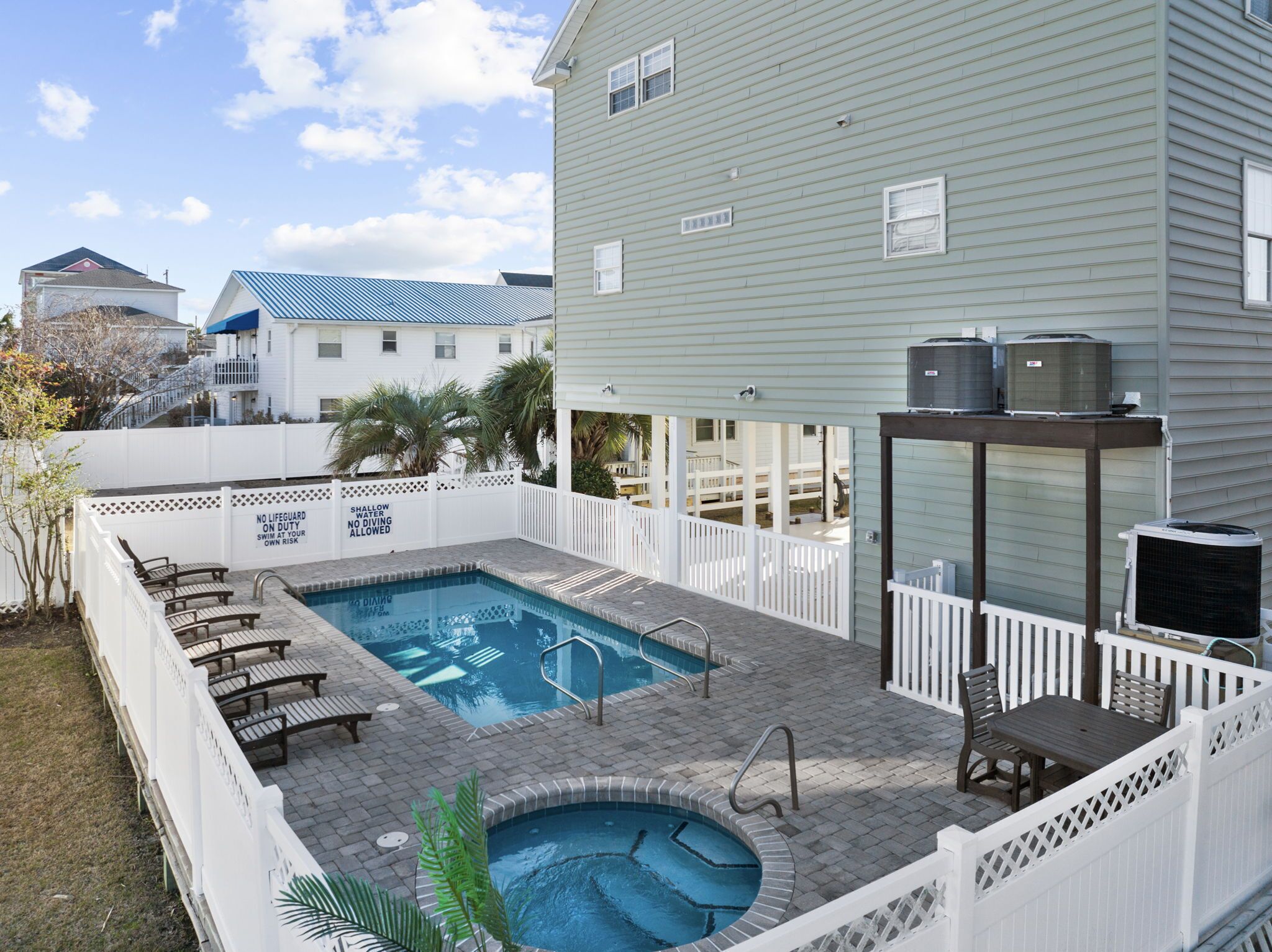A backyard with a swimming pool, lounge chairs, and an outdoor kitchen area.