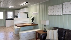 A compact living space with a kitchenette, a dining area, and a seating area with a couch and a side table. - Short walk to Beach, 2 Bedroom/1 Bath Quad 3 (up) w/pool access near Main St (North Myrtle Beach)