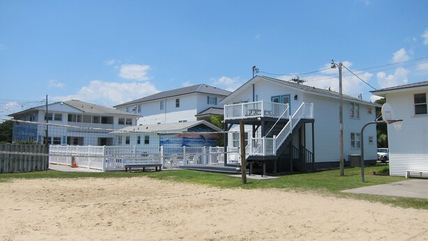 A beachfront property with a two-story house featuring a balcony and a small deck. - Short walk to Beach, 2 Bedroom/1 Bath Quad 4 (up) w/pool access near Main St (North Myrtle Beach)