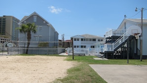 Une propriété située en bord de mer, avec une plage de sable, une clôture blanche et un bâtiment doté d’un balcon.