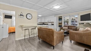 Un salon moderne avec un canapé marron, une table basse et un téléviseur fixé au mur.