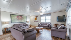 Ein Wohnzimmer mit zwei Sofas, einem Couchtisch, einem Fernseher und Kunstwerken an den Wänden.