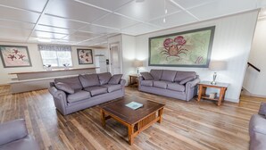 Ein geräumiges Wohnzimmer mit zwei grauen Sofas, einem Holztisch und einem großen Gemälde an der Wand.