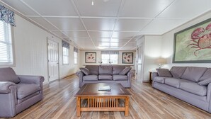 Ein geräumiges Wohnzimmer mit einem Holztisch, zwei grauen Sofas und einem großen Gemälde an der Wand.
