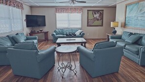A living room with a ceiling fan, a flat-screen TV, and a large painting on the wall. - Short walk from beach, 5 Bedroom/3 Bath Duplex-10-plenty of room for groups (North Myrtle Beach)