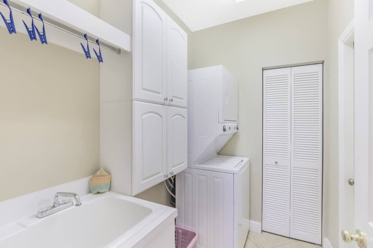 A bathroom with a bathtub, a white sink, a towel rack, a laundry machine, and a white door.