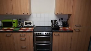 Een keuken met houten kastjes, een magnetron, een broodrooster, een koffiezetapparaat en een oven.