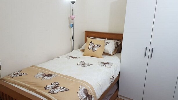 Een slaapkamer met een bed, nachtkastje, kledingkast en een lamp.