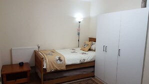 Een slaapkamer met een bed, nachtkastje, kledingkast en een radiator.