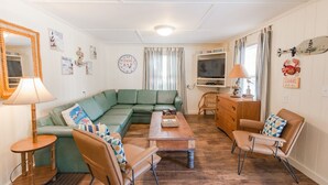 Un salon chaleureux avec un canapé vert, une table basse en bois et un téléviseur.