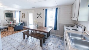 Une cuisine compacte avec un coin repas, des meubles blancs et une cuisinière.