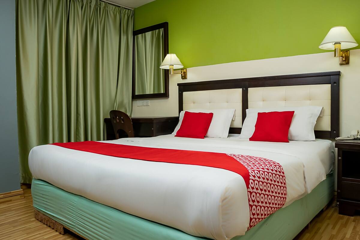 A hotel room with a large bed, green walls, and a wooden floor.