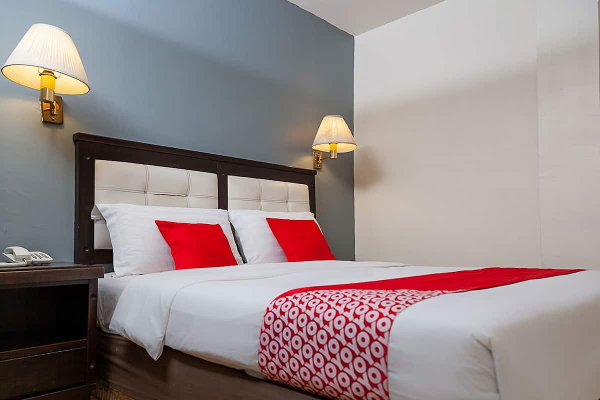 A hotel room with a bed, two bedside lamps, a nightstand, and a telephone.