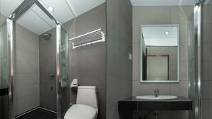 Une salle de bain moderne avec une douche à parois de verre, des toilettes et un lavabo surmonté d’un miroir.