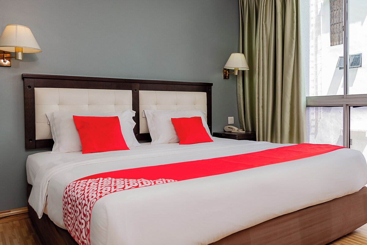 A neatly made bed with white and red bedding, a wooden headboard, and two bedside lamps.
