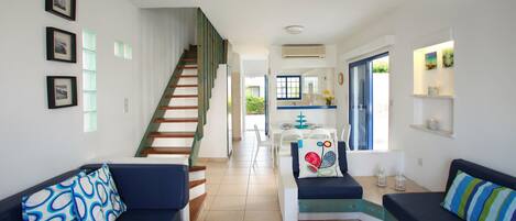 Una sala de estar con una escalera, dos sofás, un comedor y una cocina.