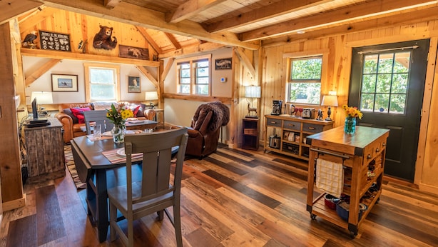 Een knus interieur van een houten hut, met een eethoek, keuken en een gezellige zithoek.