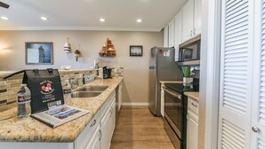 Eine moderne Küche mit Granitarbeitsplatten, Edelstahlgeräten und einer Holzrückwand.