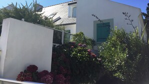 Ein modernes Haus mit weißer Fassade, einem grünen Fenster und einem Schornstein.