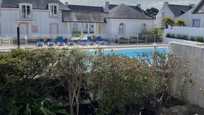 Ein Poolbereich mit Liegestühlen und Schwimmbecken, umgeben von Gebäuden mit einheitlichem Baustil.