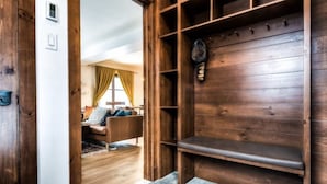 A wooden bench with a shelf and a wall-mounted clock in a room with a wooden floor and a window with curtains. - SPECTACULAR SKI IN - SKI OUT Golf Hiking Biking Casino Chalet in Mont Tremblant  (Mont-Tremblant)