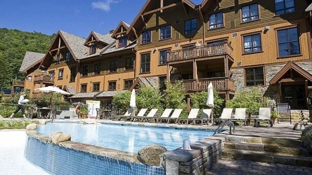 A resort with a pool, lounge chairs, and wooden buildings. - SPECTACULAR SKI IN - SKI OUT Golf Hiking Biking Casino Chalet in Mont Tremblant  (Mont-Tremblant)