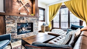 A cozy living room with a stone fireplace, leather sofa, and a flat-screen TV. - SPECTACULAR SKI IN - SKI OUT Golf Hiking Biking Casino Chalet in Mont Tremblant  (Mont-Tremblant)