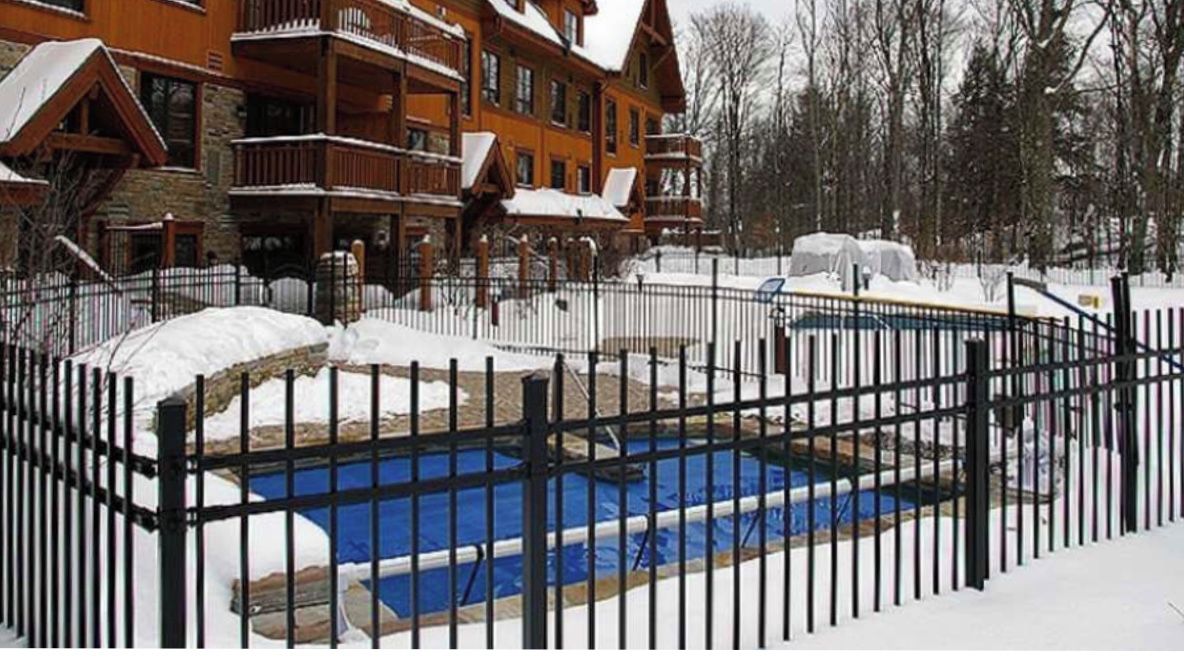 Eine Holzhütte mit einem eingezäunten Schwimmbecken.