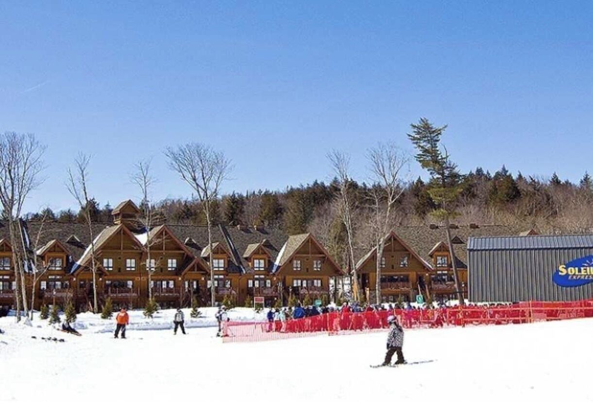 Un chalet comprenant plusieurs cabanes en bois et un grand bâtiment avec une enseigne.