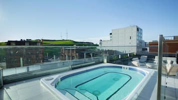 Relax on the rooftop terrace with a hot tub, lounge chairs, and a small table.