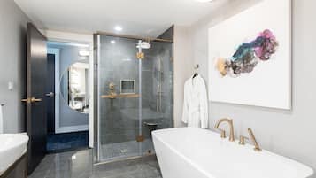 A modern bathroom with a freestanding bathtub, a glass-enclosed shower, and a large mirror.