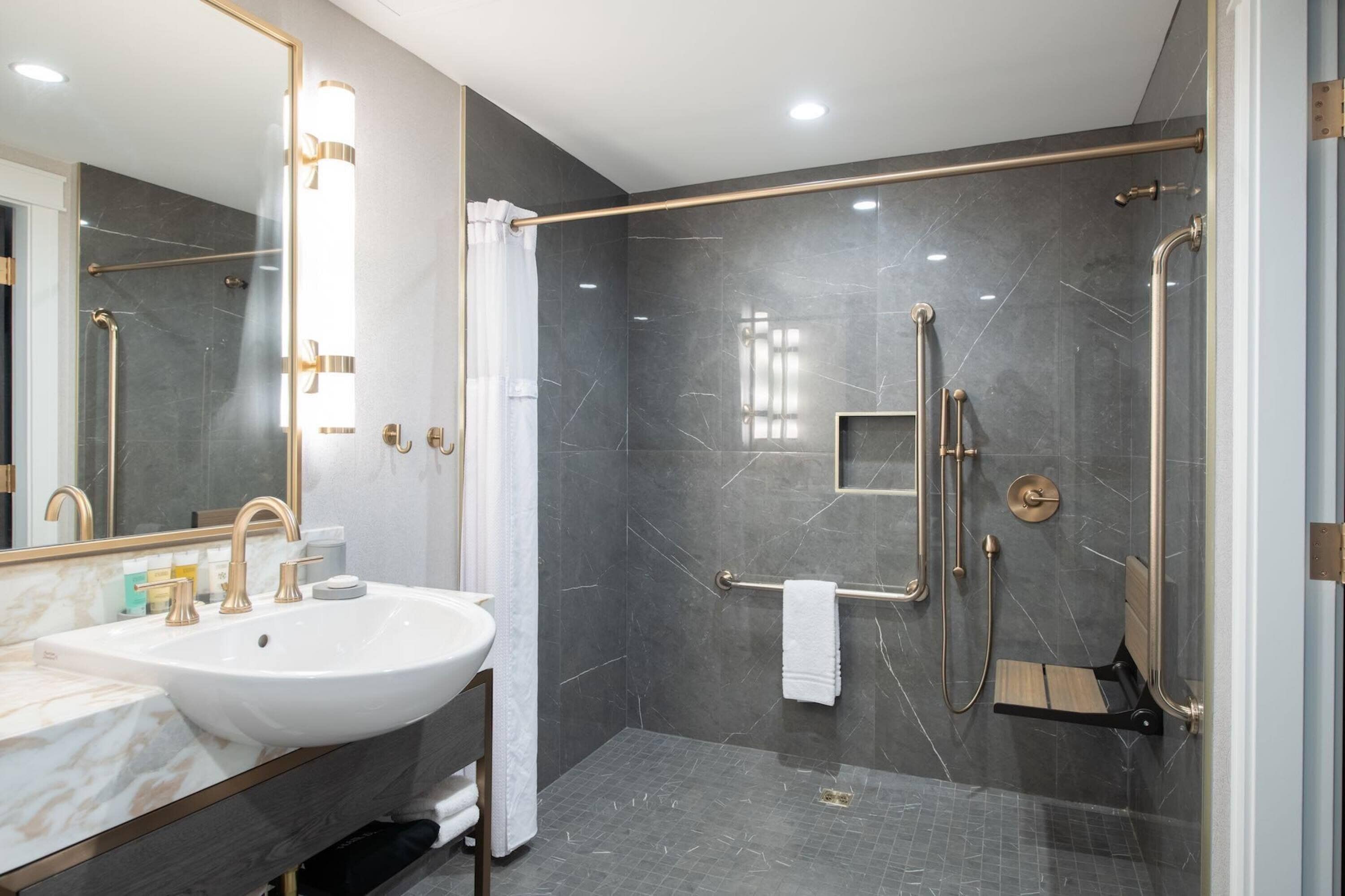 A modern bathroom with a large sink, mirror, and walk-in shower.