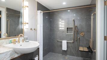 A modern bathroom with a large sink, mirror, and walk-in shower.